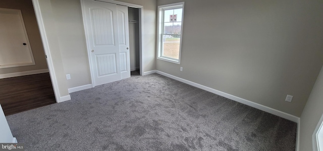 unfurnished bedroom with dark carpet and a closet