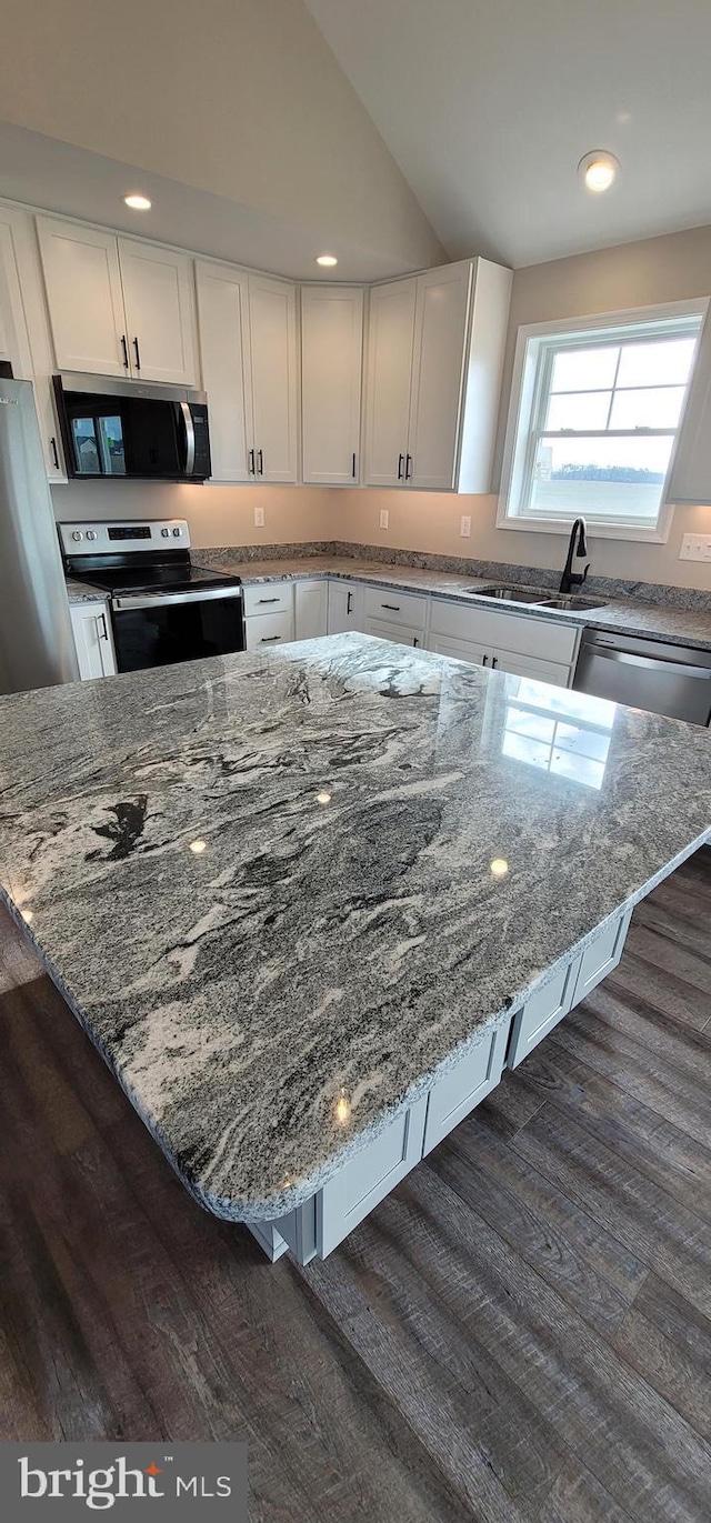 kitchen with stainless steel appliances, light stone counters, white cabinets, and a kitchen bar