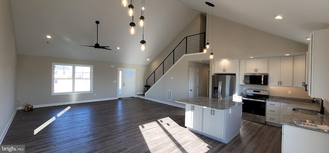 kitchen with white cabinetry, sink, a center island, stainless steel appliances, and light stone countertops