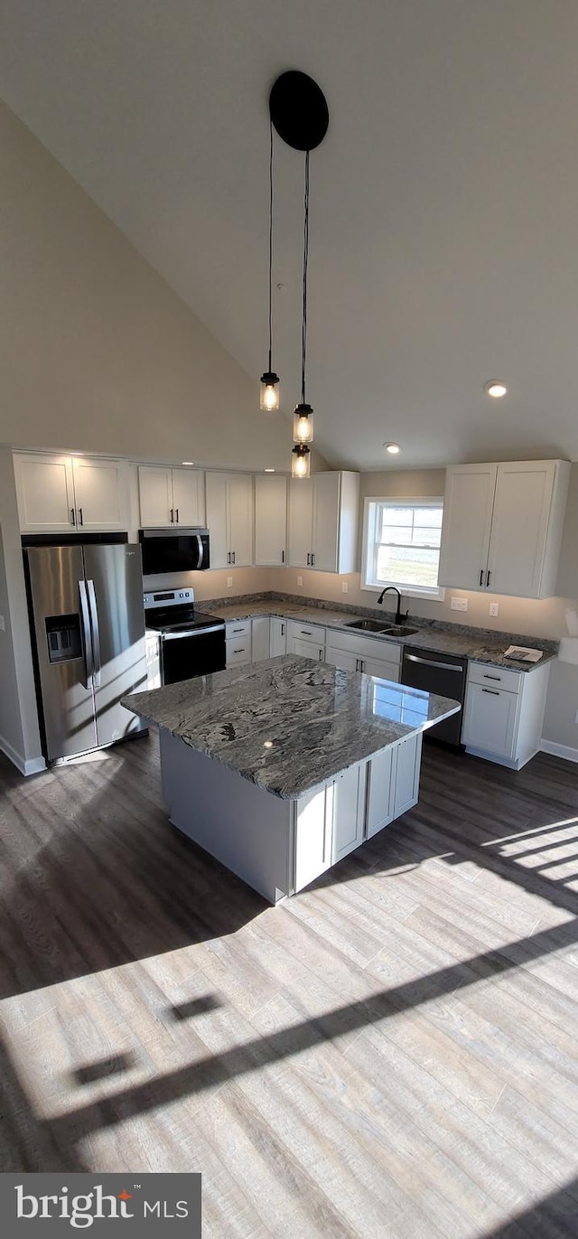 kitchen featuring pendant lighting, stainless steel appliances, white cabinets, and a kitchen island