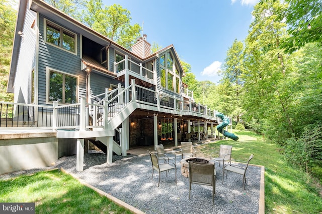 rear view of house with a yard, a patio, a fire pit, and a wooden deck