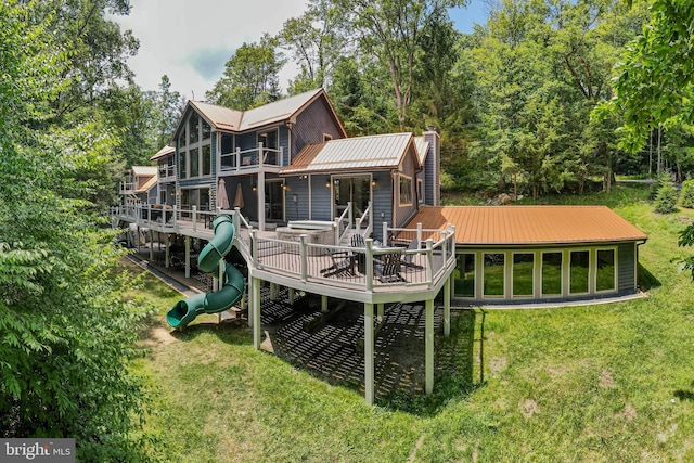 back of property with a lawn, a deck, and a playground