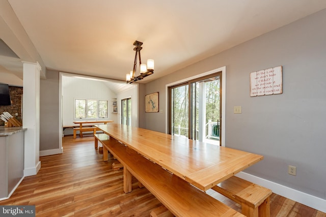 dining room featuring a chandelier, lofted ceiling, and light hardwood / wood-style flooring