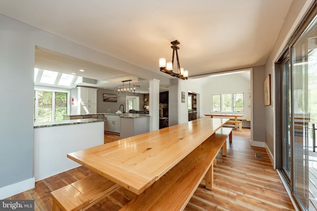 dining space with a skylight, a wealth of natural light, and light hardwood / wood-style flooring