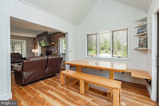 dining area featuring lofted ceiling, a healthy amount of sunlight, light hardwood / wood-style floors, and a fireplace