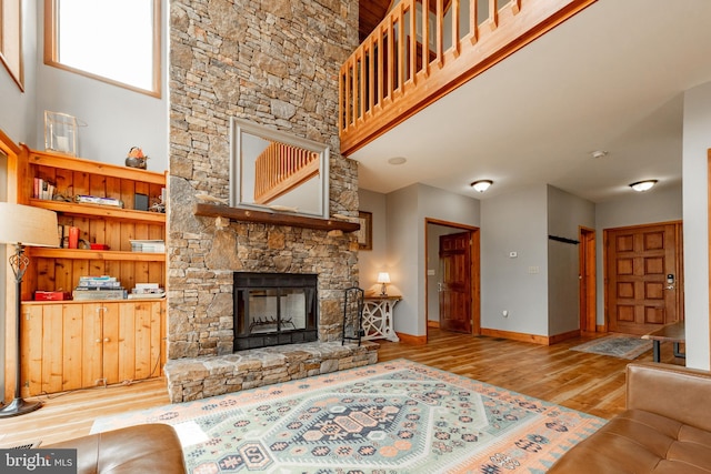 living room with a fireplace, a high ceiling, and light hardwood / wood-style flooring