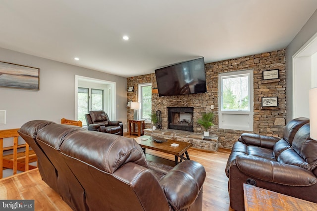 living room featuring a stone fireplace and light wood-type flooring