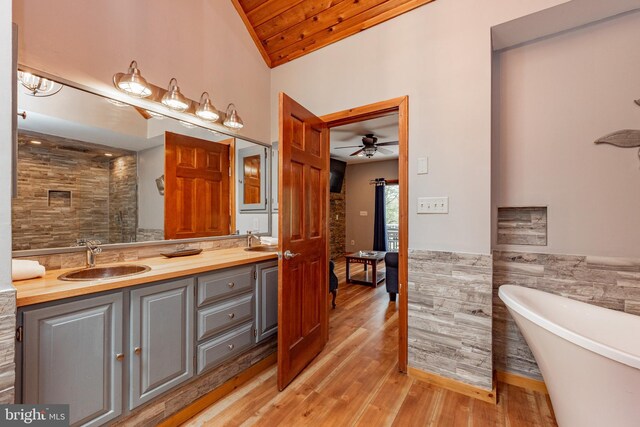 bathroom featuring ceiling fan, wooden ceiling, hardwood / wood-style floors, lofted ceiling, and tile walls