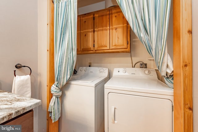 clothes washing area with washer and clothes dryer and cabinets