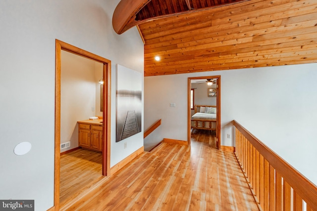 hall featuring light wood-type flooring, wood ceiling, and vaulted ceiling