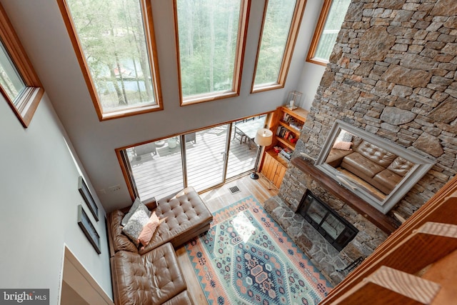 living room featuring light wood-type flooring, a fireplace, and a high ceiling