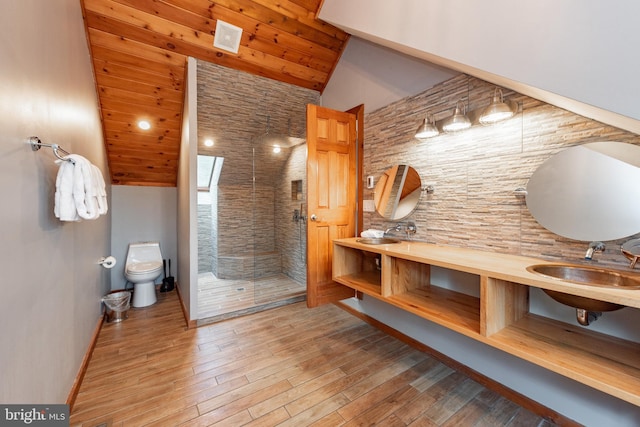 bathroom with wood-type flooring, vaulted ceiling, tiled shower, toilet, and wood ceiling