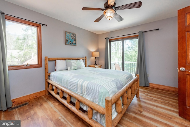 bedroom featuring access to exterior, light hardwood / wood-style floors, multiple windows, and ceiling fan