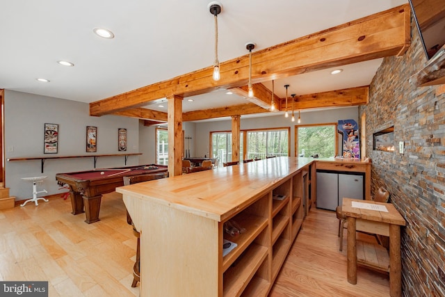 kitchen with kitchen peninsula, light wood-type flooring, decorative light fixtures, and butcher block counters