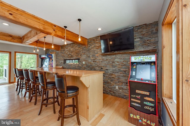 bar with decorative light fixtures, beam ceiling, wood counters, and light wood-type flooring