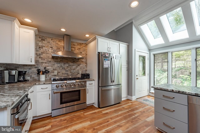 kitchen featuring white cabinetry, wall chimney range hood, and appliances with stainless steel finishes