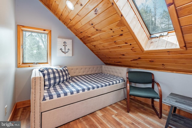 bedroom with multiple windows, wooden ceiling, light hardwood / wood-style floors, and lofted ceiling with skylight