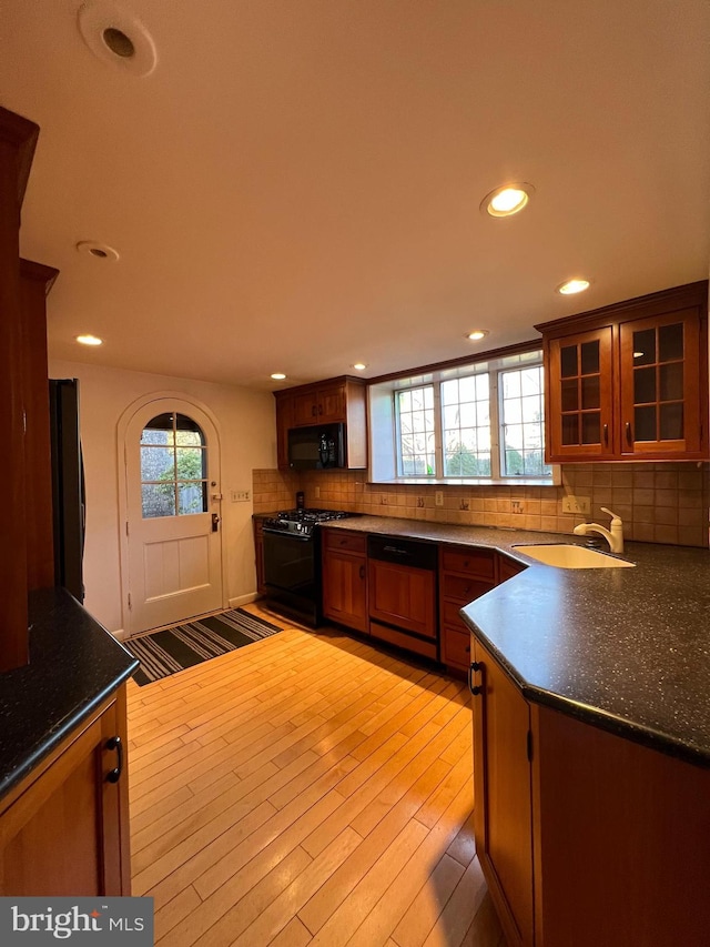 kitchen with sink, light hardwood / wood-style flooring, backsplash, and black appliances