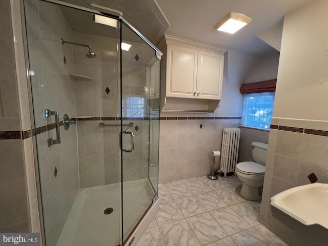 bathroom featuring tile walls, radiator heating unit, a shower with shower door, and toilet