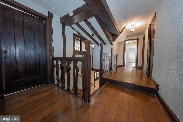 corridor with hardwood / wood-style flooring, lofted ceiling with beams, and a textured ceiling