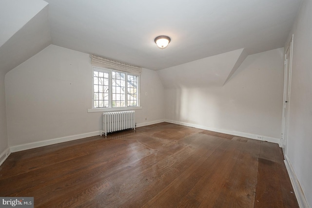 bonus room featuring dark wood-type flooring, radiator heating unit, and vaulted ceiling