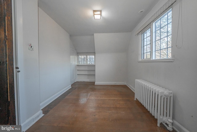 bonus room with radiator, vaulted ceiling, and dark hardwood / wood-style floors