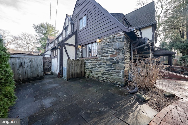 view of side of home with a storage shed and a patio