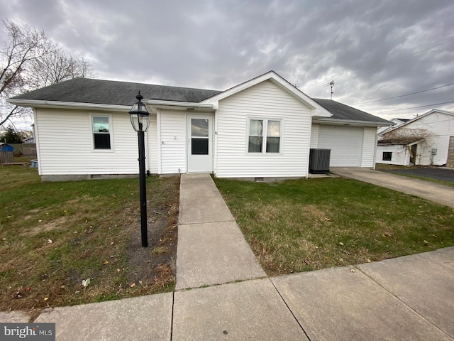 view of front of home with a front yard, central AC, and a garage