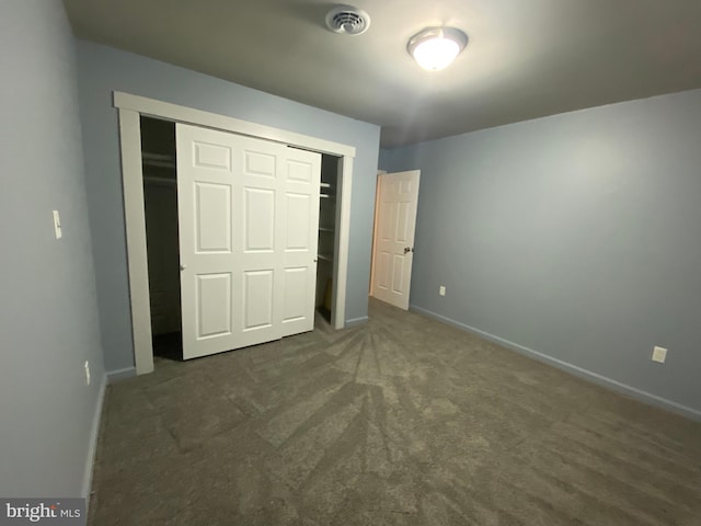 unfurnished bedroom featuring dark carpet and a closet