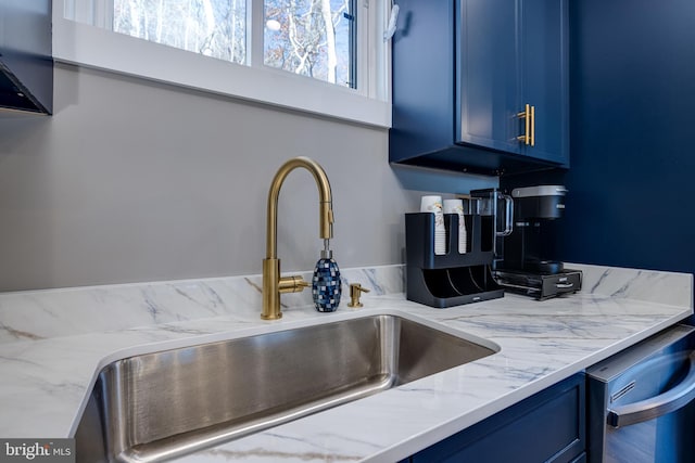 details featuring blue cabinetry, light stone countertops, and sink