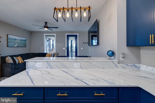 kitchen with pendant lighting, ceiling fan, light stone counters, and blue cabinetry