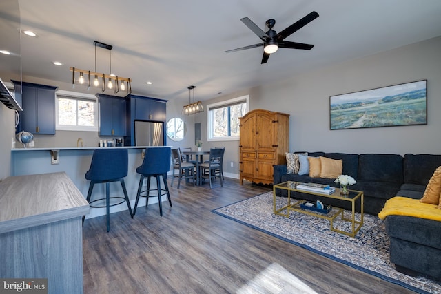 living room with ceiling fan with notable chandelier, dark hardwood / wood-style flooring, and a healthy amount of sunlight