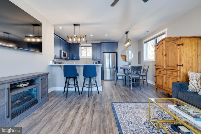 living room with plenty of natural light, ceiling fan, and dark wood-type flooring