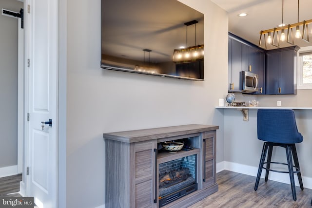 kitchen with kitchen peninsula, a kitchen breakfast bar, decorative light fixtures, and dark hardwood / wood-style floors