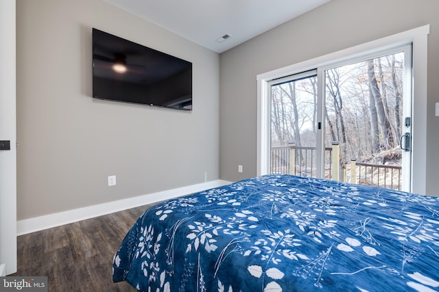 bedroom featuring multiple windows, dark hardwood / wood-style flooring, and access to exterior