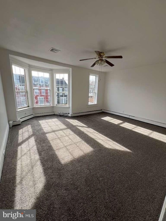 spare room featuring ceiling fan, carpet, and a baseboard heating unit