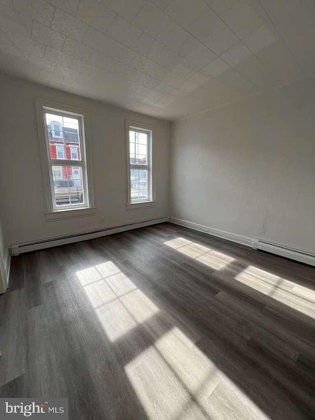 unfurnished room with hardwood / wood-style flooring and baseboard heating