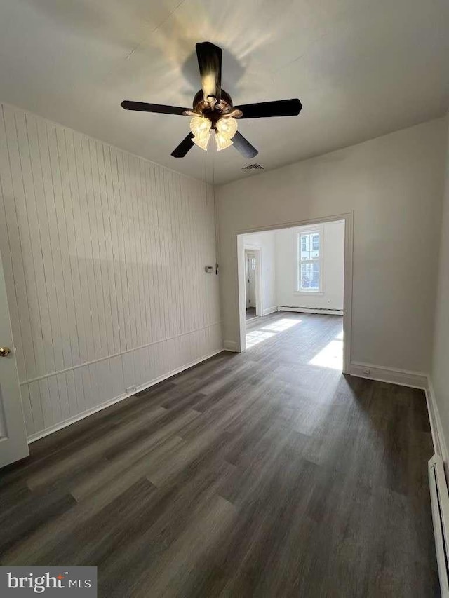 empty room featuring ceiling fan, dark hardwood / wood-style flooring, and baseboard heating