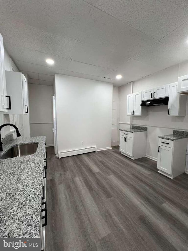 kitchen featuring a baseboard heating unit, sink, dark hardwood / wood-style floors, light stone countertops, and white cabinetry