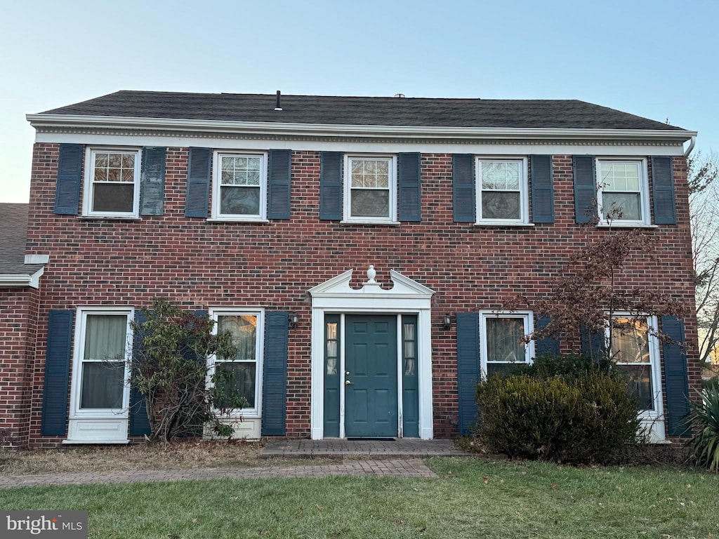 colonial inspired home with a front lawn