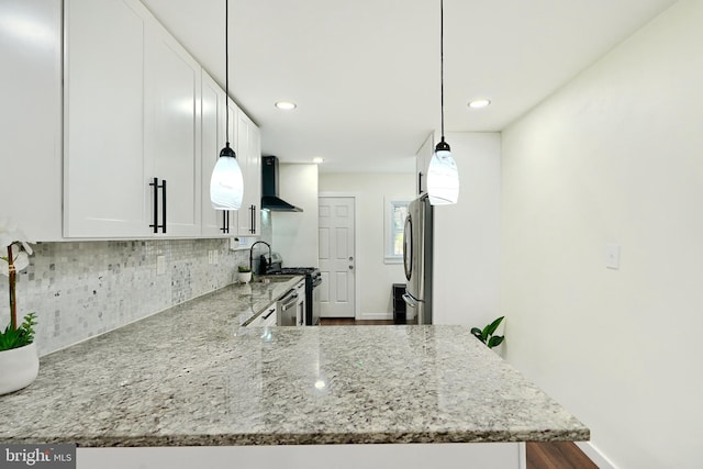 kitchen with white cabinets, kitchen peninsula, appliances with stainless steel finishes, and wall chimney range hood