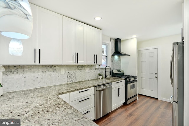 kitchen featuring white cabinets, wall chimney range hood, and appliances with stainless steel finishes