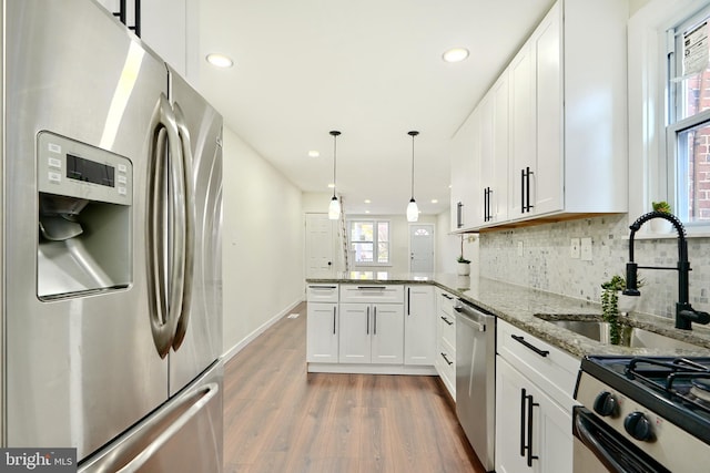 kitchen featuring a wealth of natural light, white cabinetry, hardwood / wood-style floors, and stainless steel appliances