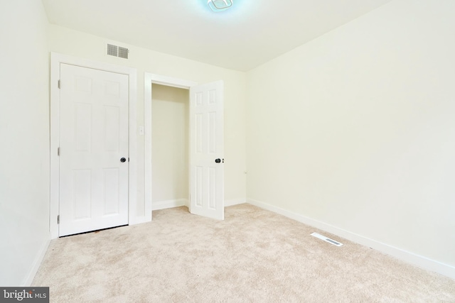 unfurnished bedroom with light carpet and a closet