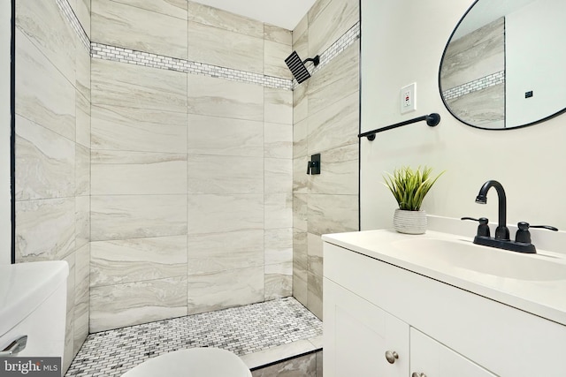 bathroom with tiled shower, vanity, and toilet