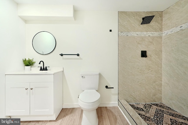 bathroom featuring tiled shower, hardwood / wood-style floors, vanity, and toilet