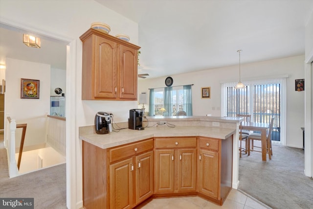 kitchen featuring kitchen peninsula, pendant lighting, and light colored carpet