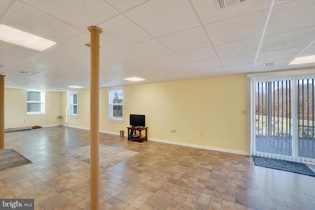 basement with a paneled ceiling, a wealth of natural light, and a baseboard heating unit