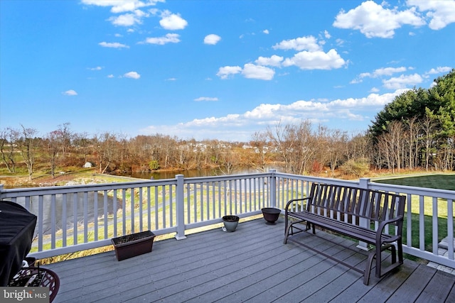 wooden terrace with a yard, a water view, and a grill