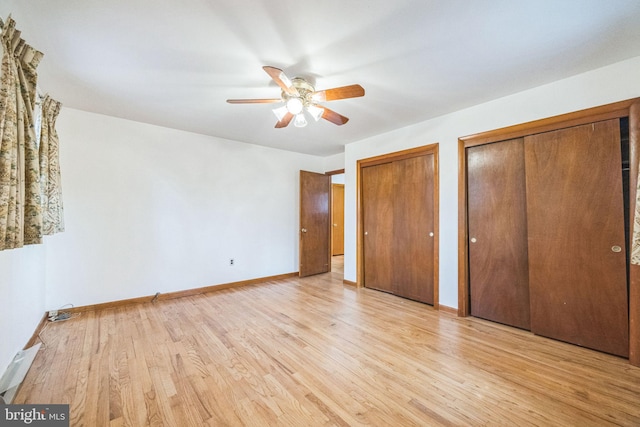 unfurnished bedroom with two closets, light hardwood / wood-style floors, and ceiling fan